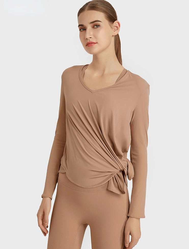 Woman in stylish loose top with long sleeves and V-neckline, ideal for yoga. Comfortable and breathable with quick-dry fabric.